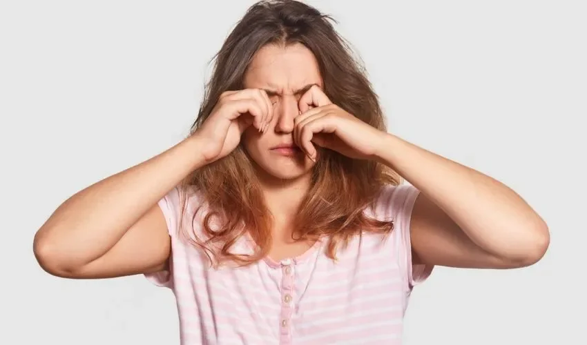 Vista de una mujer frontándose los ojos. 