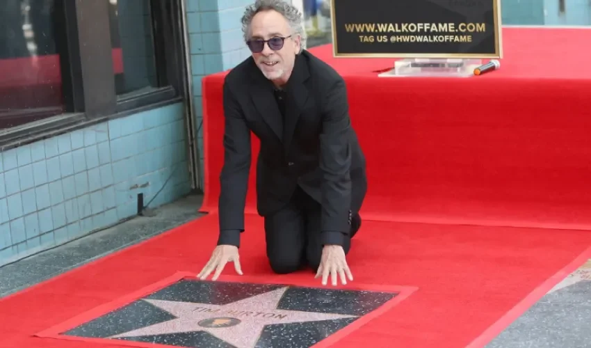 Tim Burton se arrodilla junto a su estrella durante una ceremonia en la que se le honra con una estrella en el Paseo de la Fama de Hollywood en Los Ángeles, California (EE.UU.). EFE/Nina Prommer